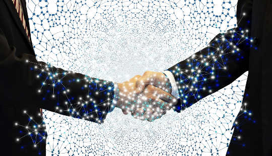 4 Strategies for Negotiating Well two business men shaking hands showing the energy connecting in both hands and arms