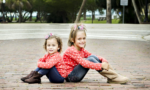 Wandering Without Whining: How to Keep Kids Engaged When Travelling two smiling young sisters sitting back to back